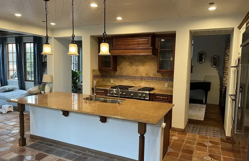 Remodeled kitchen with granite island, dark wood cabinets, and pendant lighting