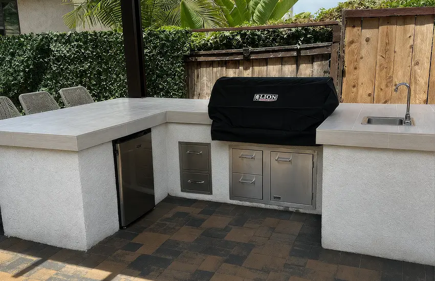 Built-in outdoor kitchen with stainless grill, sink, and paver patio