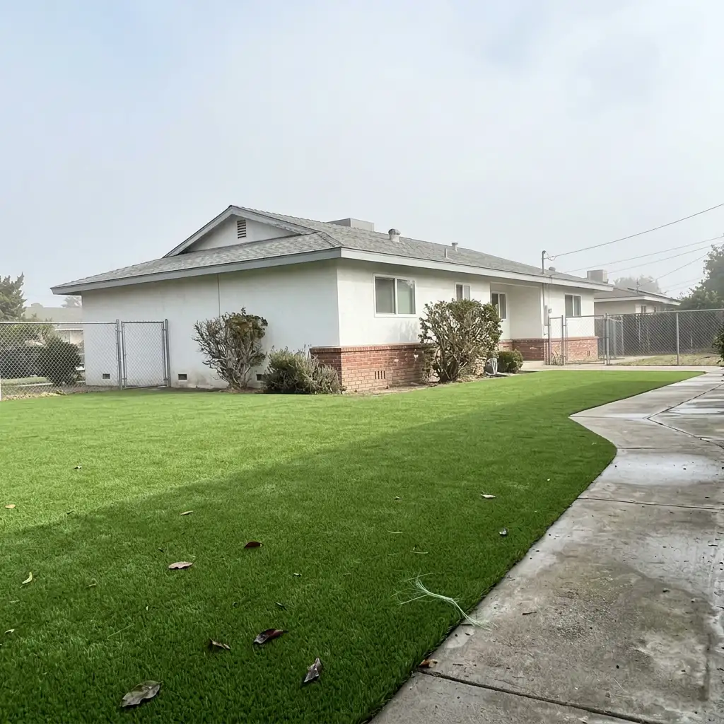 Finished artificial turf backyard lawn with even green blades and clean-cut edges against a concrete path