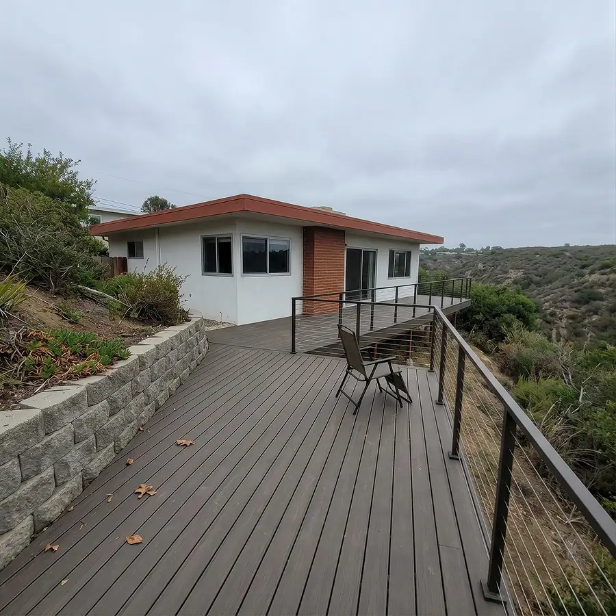 Composite deck with cable railing and a retaining wall on a La Mesa canyon-edge lot with the East County ridge across the gap